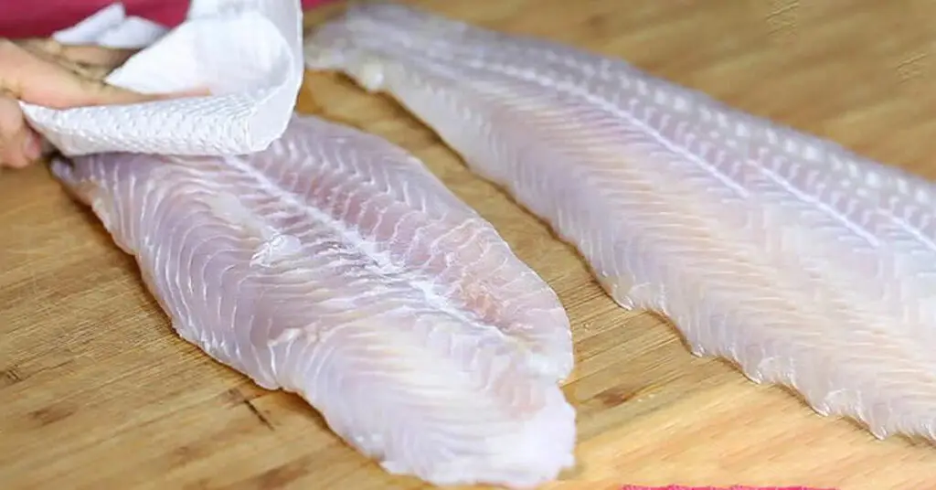 Làm khô cá bằng khăn giấy trước khi rán giúp da se lại và không bị dính chảo.